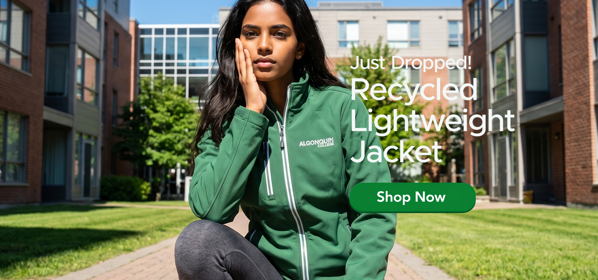 A person sits outdoors on a sunny day wearing a green “Algonquin College” jacket. Modern brick-and-glass campus buildings, trees, and grass surround them. On the right, overlaid text reads “Just Dropped! Recycled Lightweight Jacket” above a green “Shop Now” button.
